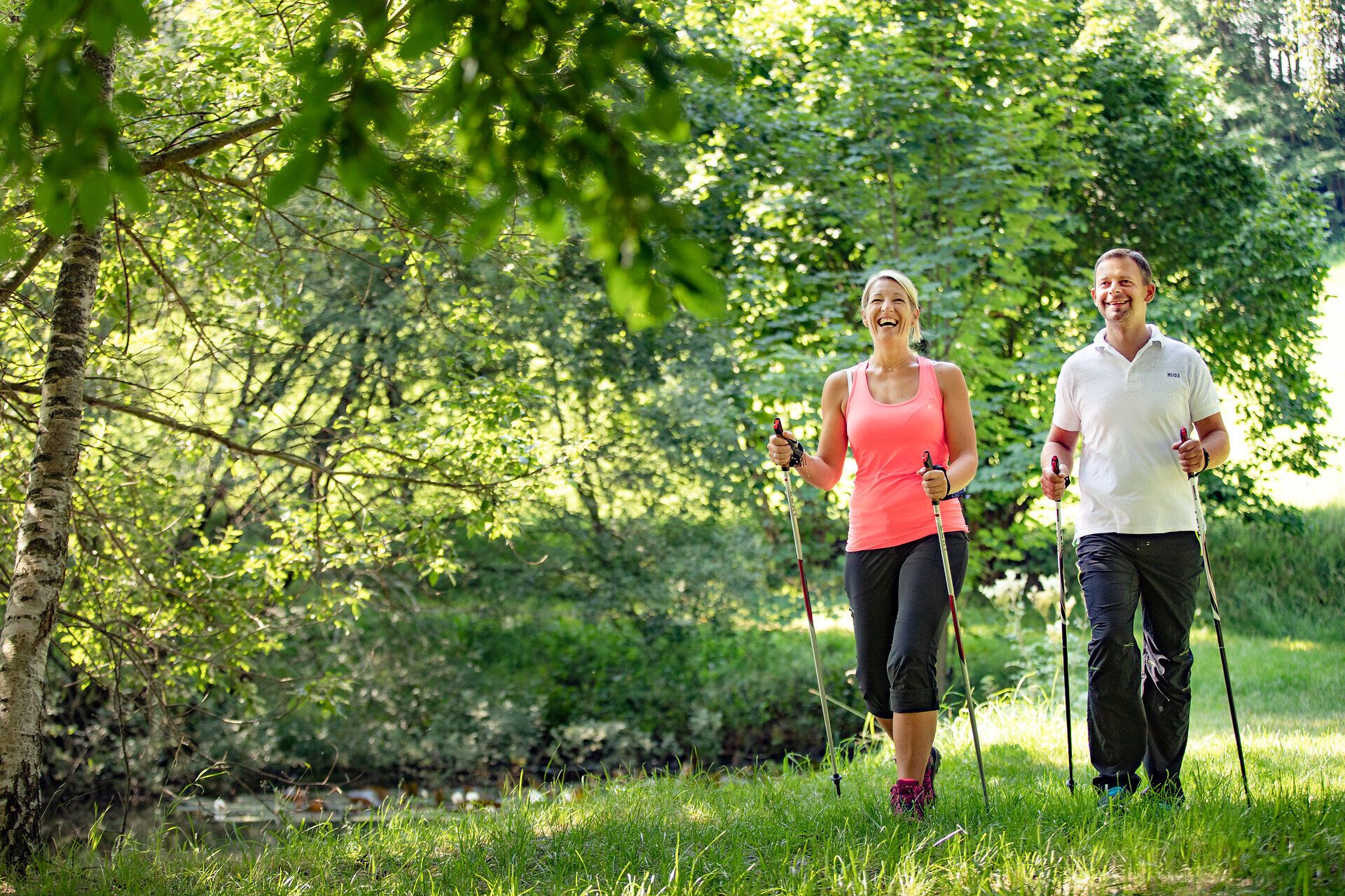 In der malerischen Umgebung von Moorbad Bad Großpertholz genießen zwei fröhliche Wanderer die frische Luft und die Schönheit der Natur beim Nordic Walking. Umgeben von üppigem Grün und dem sanften Licht der Sonne strahlt die Szenerie eine einladende und entspannende Atmosphäre aus, die zum Verweilen einlädt.