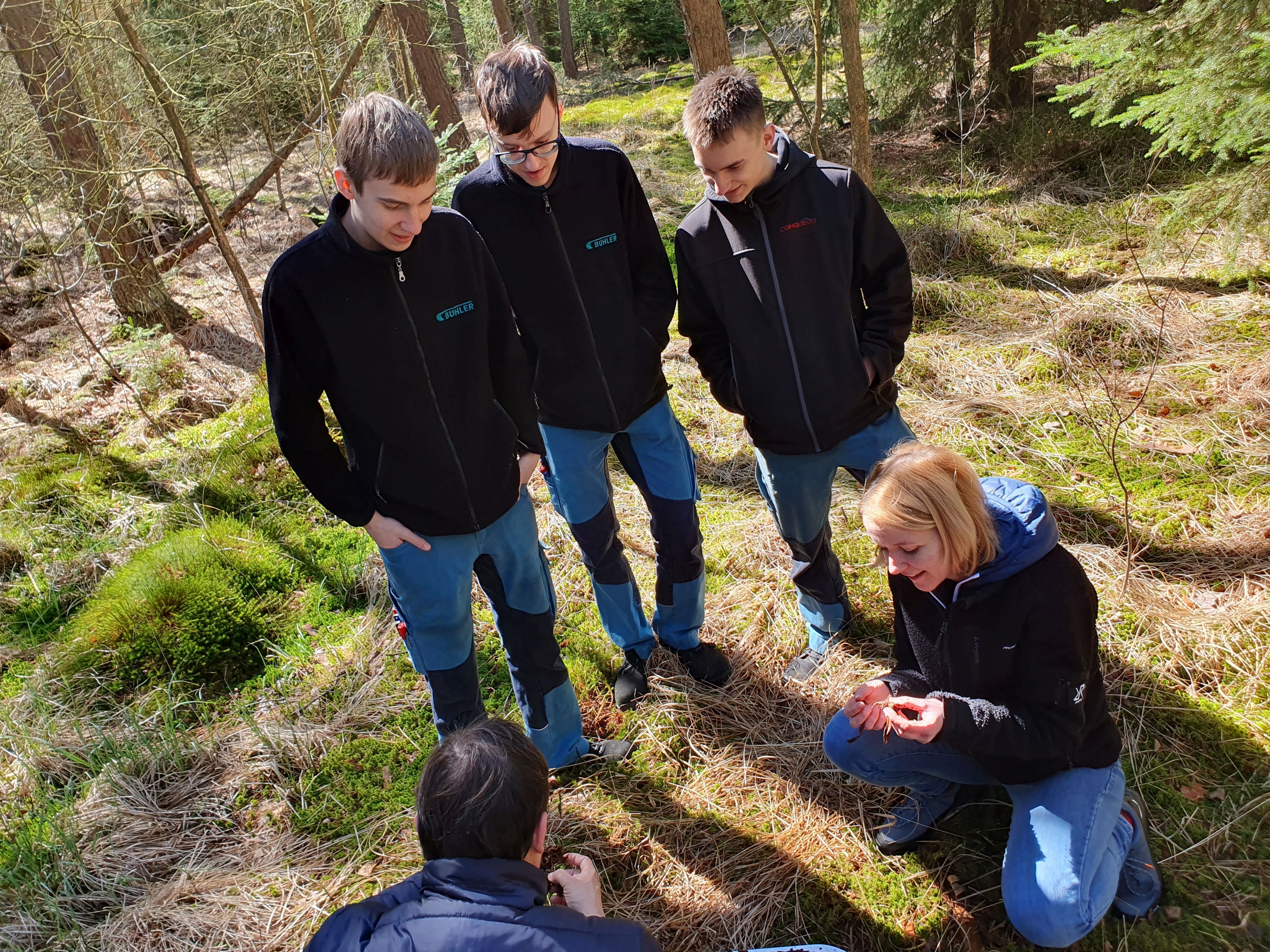 Eine Gruppe Menschen die eine Bodenprobe aus dem Moor betrachtet.