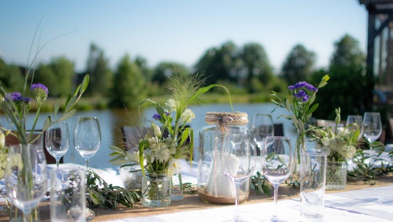 Festlich gedeckter Tisch im Freien mit Blumen und Gläsern.
