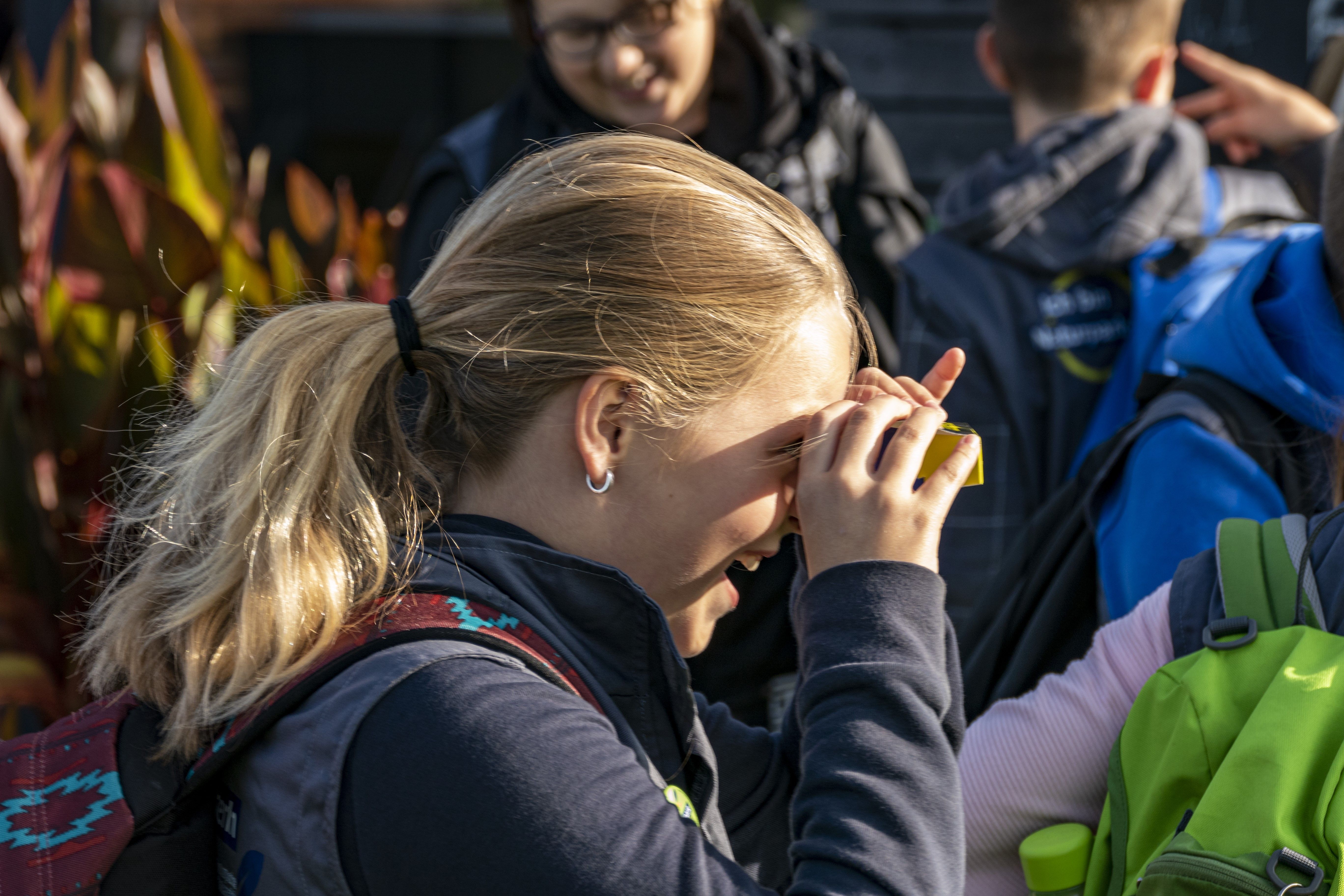 Ein Mädchen schaut durch ein Mini-Fernglas